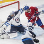 
              Winnipeg Jets goaltender Connor Hellebuyck stops Montreal Canadiens' Kirby Dach (77) as Jets' Nate Schmidt (88) and Ville Heinola (14) defend during the first period of an NHL hockey game, Tuesday, Jan. 17, 2023 in Montreal. (Graham Hughes/The Canadian Press via AP)
            