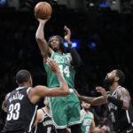 
              Boston Celtics center Robert Williams III (44) shoots as Brooklyn Nets center Nic Claxton (33) and guard Kyrie Irving (11) defend during the first half of an NBA basketball game Thursday, Jan. 12, 2023, in New York. (AP Photo/Mary Altaffer)
            