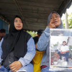 
              Rini Hanifah, holds a picture of her son Agus Riyansah who was a victim in the October deadly crowd surge, as she waits outside a court building in Surabaya, East Java, Indonesia, Monday, Jan, 16, 2023. An Indonesian court began trial Monday against five men on charges of negligence leading to deaths of 135 people after police fired tear gas inside a soccer stadium, setting off a panicked run for the exits in which many were crushed. (AP Photo/Trisnadi)
            