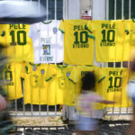 
              Jerseys for sale featuring the player number and name of Pele hang where people walk to the Vila Belmiro stadium where the late Brazilian soccer great lies in state in Santos, Brazil, Monday, Jan. 2, 2023. (AP Photo/Matias Delacroix)
            