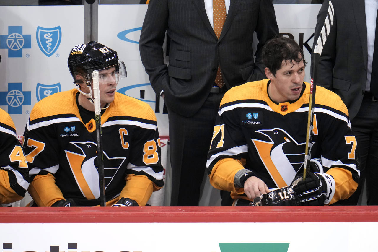 Pittsburgh Penguins' Sidney Crosby (87) and Evgeni Malkin (71) sit on the bench during the first pe...