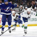
              Vancouver Canucks center J.T. Miller (9) gets held by Tampa Bay Lightning left wing Nicholas Paul (20) for a penalty during the third period of an NHL hockey game Thursday, Jan. 12, 2023, in Tampa, Fla. (AP Photo/Chris O'Meara)
            
