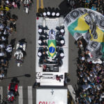 
              The casket of late Brazilian soccer great Pele is draped in the Brazilian and Santos FC soccer club flags as his remains are transported from Vila Belmiro stadium, where he laid in state, to the cemetery during his funeral procession in Santos, Brazil, Tuesday, Jan. 3, 2023. (AP Photo/Matias Delacroix)
            
