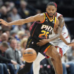 
              Phoenix Suns forward Mikal Bridges, front, pursues a loose ball with Denver Nuggets guard Kentavious Caldwell-Pope in the first half of an NBA basketball game Wednesday, Jan. 11, 2023, in Denver. (AP Photo/David Zalubowski)
            