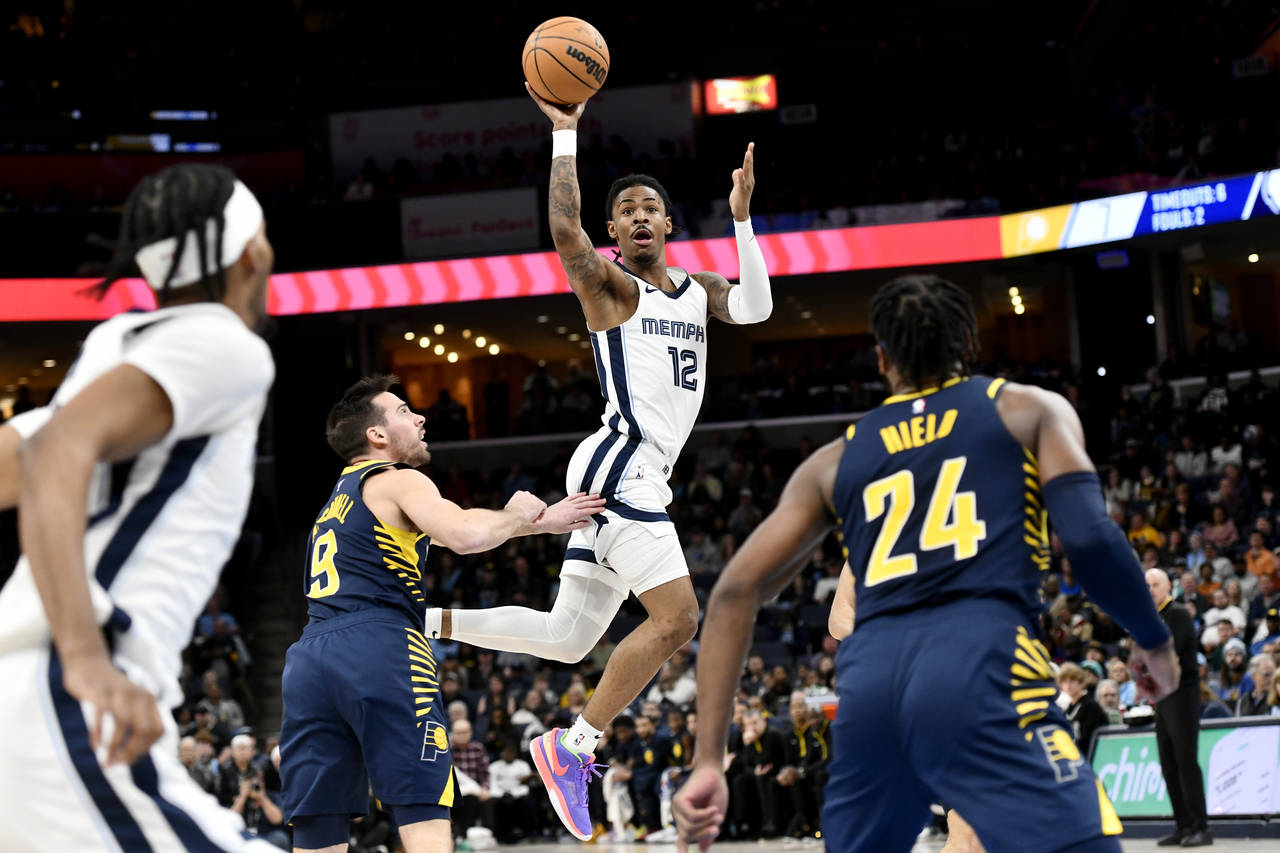 Memphis Grizzlies guard Ja Morant (12) passes the ball over Indiana Pacers guard T.J. McConnell (9)...