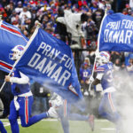 
              The Buffalo Bills carry flags onto the field displaying the number 3 in support of safety Damar Hamlin before an NFL football game against the New England Patriots, Sunday, Jan. 8, 2023, in Orchard Park, N.Y. Hamlin remains hospitalized after suffering a catastrophic on-field collapse in the team's previous game against the Cincinnati Bengals. (AP Photo/Jeffrey T. Barnes)
            