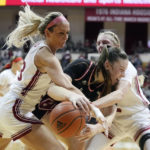 
              Nebraska's Isabelle Bourne, center, is trapped by Indiana's Sydney Parrish, left, and Lexus Bargesser during the first half of an NCAA college basketball game, Sunday, Jan. 1, 2023, in Bloomington, Ind. (AP Photo/Darron Cummings)
            