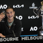 
              Aryna Sabalenka of Belarus holds up a glass of champagne at a press conference as she sits next to the Daphne Akhurst Memorial Trophy after defeating Elena Rybakina of Kazakhstan in the women's singles final at the Australian Open tennis championship in Melbourne, Australia, Saturday, Jan. 28, 2023. (AP Photo/Dita Alangkara)
            