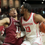 
              Houston's J'Wan Roberts (13) charges into Temple's Nick Jourdain (11) during the first half of an NCAA college basketball game Sunday, Jan. 22, 2023, in Houston. (AP Photo/David J. Phillip)
            