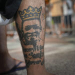 
              A soccer fan with a tattoo depicting the late Brazilian soccer legend Pele sits outside the Vila Belmiro stadium where his body lies in state for his wake in Santos, Brazil, early Tuesday, Jan. 3, 2023. (AP Photo/Matias Delacroix)
            