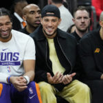 
              Phoenix Suns guard Devin Booker smiles from the bench during the second half of an NBA basketball game against the Charlotte Hornets, Tuesday, Jan. 24, 2023, in Phoenix. (AP Photo/Matt York)
            