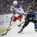 
              New York Rangers' K'Andre Miller, left, clears the puck as Columbus Blue Jackets' Johnny Gaudreau defends during the second period of an NHL hockey game on Monday, Jan. 16, 2023, in Columbus, Ohio. (AP Photo/Jay LaPrete)
            