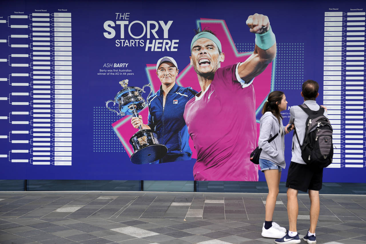 Spectators stand by an illustration of 2022 champions Ash Barty and Rafael Nadal, ahead of first ro...