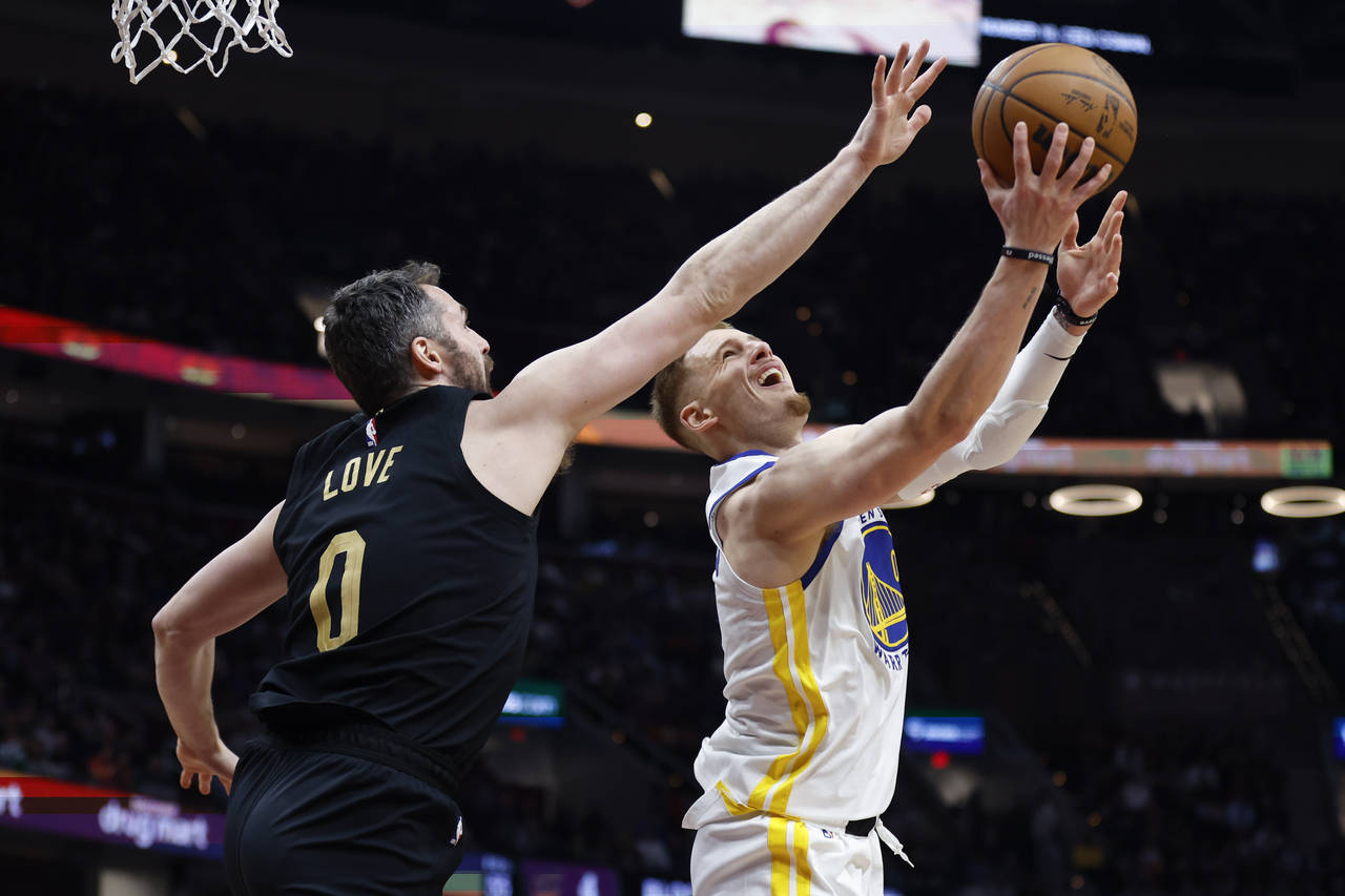 Golden State Warriors guard Donte DiVincenzo, right, shoots against Cleveland Cavaliers forward Kev...