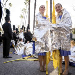 
              Rockford High School Marching Band's color guard attempts to stay warm as they wait for the 134th Rose Parade to begin in Pasadena, Calif., Monday, Jan. 2, 2023. (Sarah Reingewirtz/The Orange County Register via AP)
            