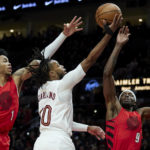 
              Cleveland Cavaliers guard Darius Garland, center, shoots between Portland Trail Blazers guard Anfernee Simons, left, and forward Jerami Grant during the first half of an NBA basketball game in Portland, Ore., Thursday, Jan. 12, 2023. (AP Photo/Craig Mitchelldyer)
            