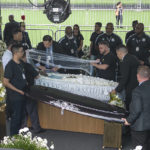 
              Funeral workers uncover the coffin of the late Brazilian soccer great Pele as he lies in state on the pitch during his wake at Vila Belmiro stadium in Santos, Brazil, Monday, Jan. 2, 2023. (AP Photo/Matias Delacroix)
            