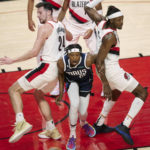 
              Dallas Mavericks guard Frank Ntilikina, center, reacts as the balls rolls out of bounds, while Portland Trail Blazers forward Drew Eubanks, left, and forward Jerami Grant watch during the first half of an NBA basketball game in Portland, Ore., Saturday, Jan. 14, 2023. (AP Photo/Craig Mitchelldyer)
            