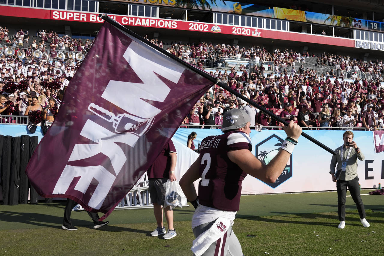 Mississippi State quarterback Will Rogers runs with a "Mike" flag in honor of former coach Mike Lea...