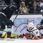 
              New York Islanders forward Brock Nelson, center, fights for the puck against Seattle Kraken defenseman Jamie Oleksiak, left, and forward Jared McCann after getting knocked to the ice during the third period of an NHL hockey game, Sunday, Jan. 1, 2023, in Seattle. The Kraken won 4-1. (AP Photo/Stephen Brashear)
            