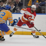 
              Calgary Flames' Dillon Dube (29) passes around St. Louis Blues' Justin Faulk (72) during the first period of an NHL hockey game Tuesday, Jan. 10, 2023, in St. Louis. (AP Photo/Jeff Roberson)
            