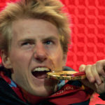 
              FILE - United States gold medalist Ted Ligety jokes with his medal during the medal ceremony for the Men's Alpine Combined at the Turin 2006 Winter Olympic Games in Turin, Italy Wednesday Feb. 15, 2006. Mikaela Shiffrin's record 83rd World Cup victory Tuesday, Jan. 24, 2023 is only the latest exploit by an American team that has been producing success after success on the circuit since Daron Rahlves and Bode Miller started it all off more than 20 years ago. (AP Photo/Greg Baker, File)
            