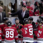 
              Chicago Blackhawks coach Luke Richardson, center, talks to the team after the Seattle Kraken scored for the fifth time in the first period of an NHL hockey game Saturday, Jan. 14, 2023, in Chicago. (AP Photo/Charles Rex Arbogast)
            