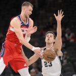 
              Washington Wizards' Kristaps Porzingis, left, passes the ball as he is defended by San Antonio Spurs' Zach Collins (23) during the first half of an NBA basketball game, Monday, Jan. 30, 2023, in San Antonio. (AP Photo/Darren Abate)
            