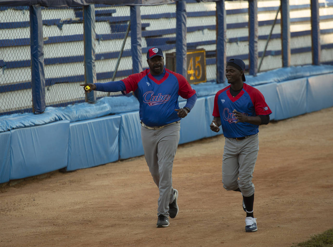 Batting coach Pedro Luis Lazo, left, and pitcher Livan Moinelo warm up as Cuban national baseball t...