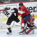 
              Florida Panthers defenseman Aaron Ekblad (5) pushes Arizona Coyotes center Laurent Dauphin (26) out of the way as goaltender Spencer Knight, right rear, makes a save during the second period of an NHL hockey game, Tuesday, Jan. 3, 2023, in Sunrise, Fla. (AP Photo/Wilfredo Lee)
            