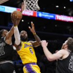 
              Los Angeles Lakers forward LeBron James, center, shoots as San Antonio Spurs forward Keita Bates-Diop, left, and center Jakob Poeltl defend during the first half of an NBA basketball game Wednesday, Jan. 25, 2023, in Los Angeles. (AP Photo/Mark J. Terrill)
            