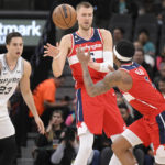 
              Washington Wizards' Kristaps Porzingis, center, passes the ball to teammate Bradley Beal, second from right, as they are defended by San Antonio Spurs' Zach Collins (23) and Jeremy Sochan, right, during the first half of an NBA basketball game, Monday, Jan. 30, 2023, in San Antonio. (AP Photo/Darren Abate)
            