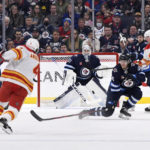 
              Calgary Flames' Rasmus Andersson (4) shoots on Winnipeg Jets goaltender Connor Hellebuyck (37) during the second period of an NHL hockey game Tuesday, Jan. 3, 2023, in Winnipeg, Manitoba. (Fred Greenslade/The Canadian Press via AP)
            