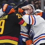 
              Vancouver Canucks' Lane Pederson, left, gets into a scuffle with Edmonton Oilers' Klim Kostin, center, and Dylan Holloway during the first period of an NHL hockey game Saturday, Jan. 21, 2023, in Vancouver, British Columbia. (Darryl Dyck/The Canadian Press via AP)
            