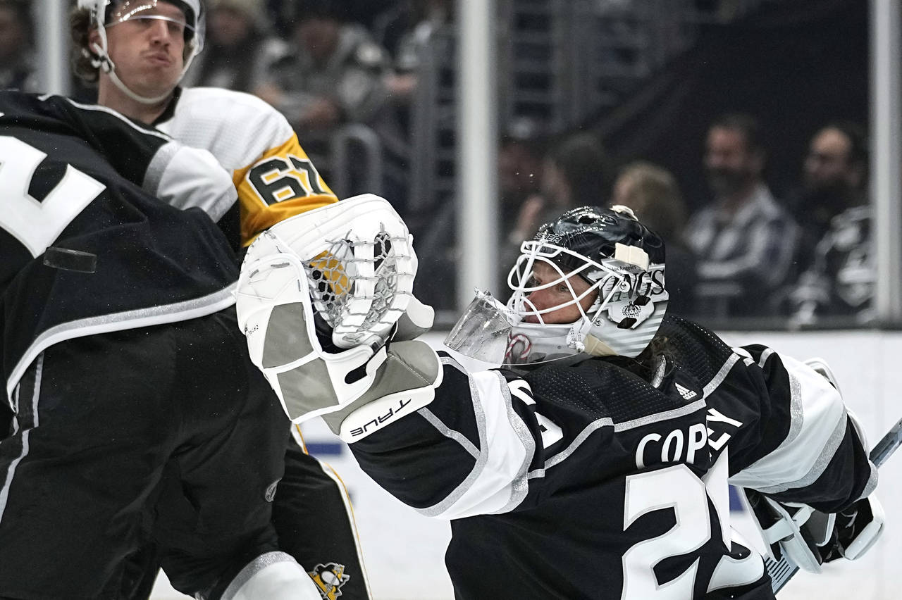 Los Angeles Kings goaltender Pheonix Copley, right, makes a glove save as Pittsburgh Penguins right...