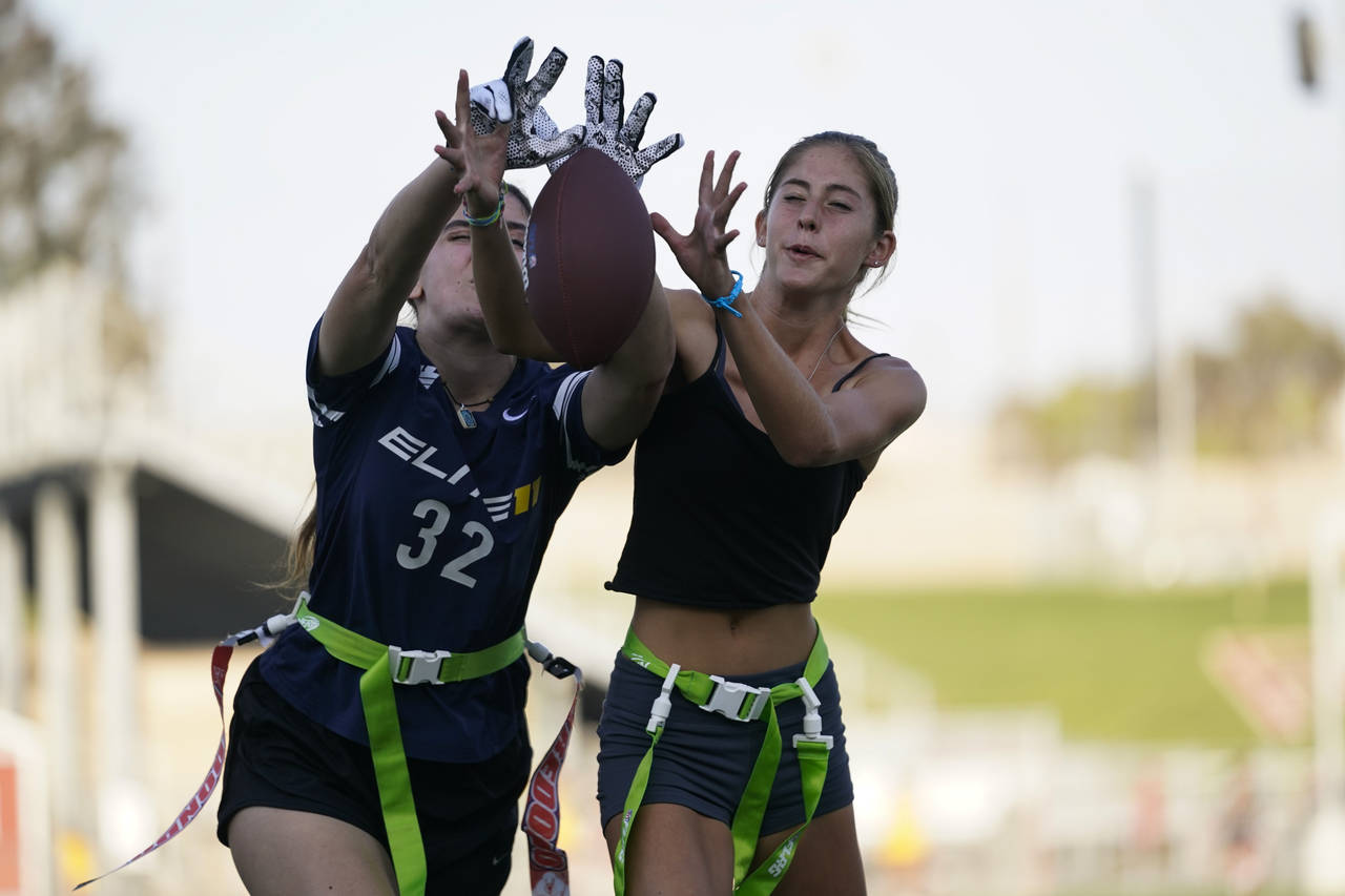 FILE - Aly Young, 17, left, and Shale Harris, 15, reach to catch a pass as they try out for the Red...