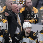 
              Boston Bruins head coach Jim Montgomery, center standing, talks to an official standing nearby in the third period of an NHL hockey game against the Dallas Stars, Tuesday, Feb. 14, 2023, in Dallas. (AP Photo/Tony Gutierrez)
            