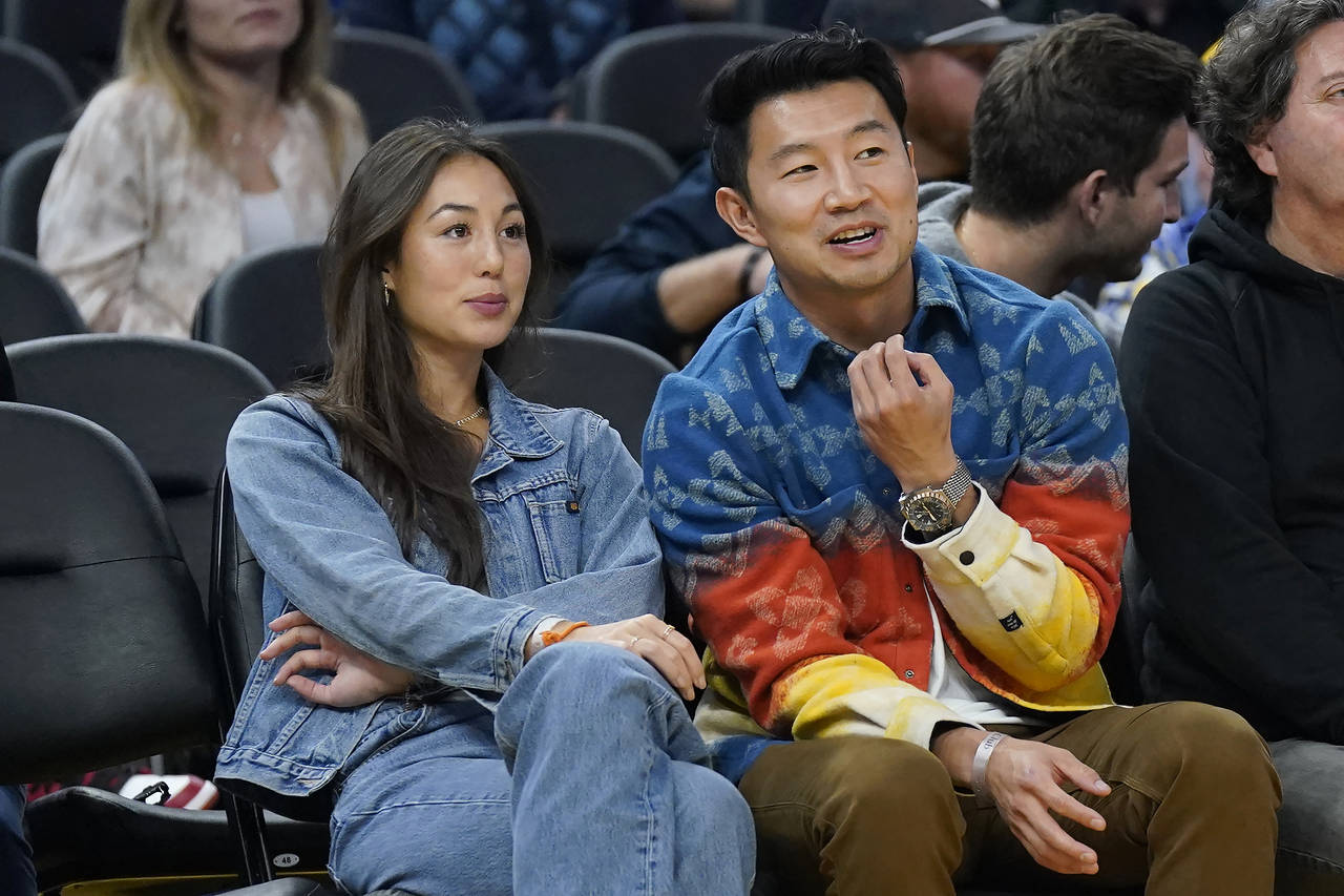 FILE - Actor Simu Liu, right, watches an NBA basketball game between the Golden State Warriors and ...