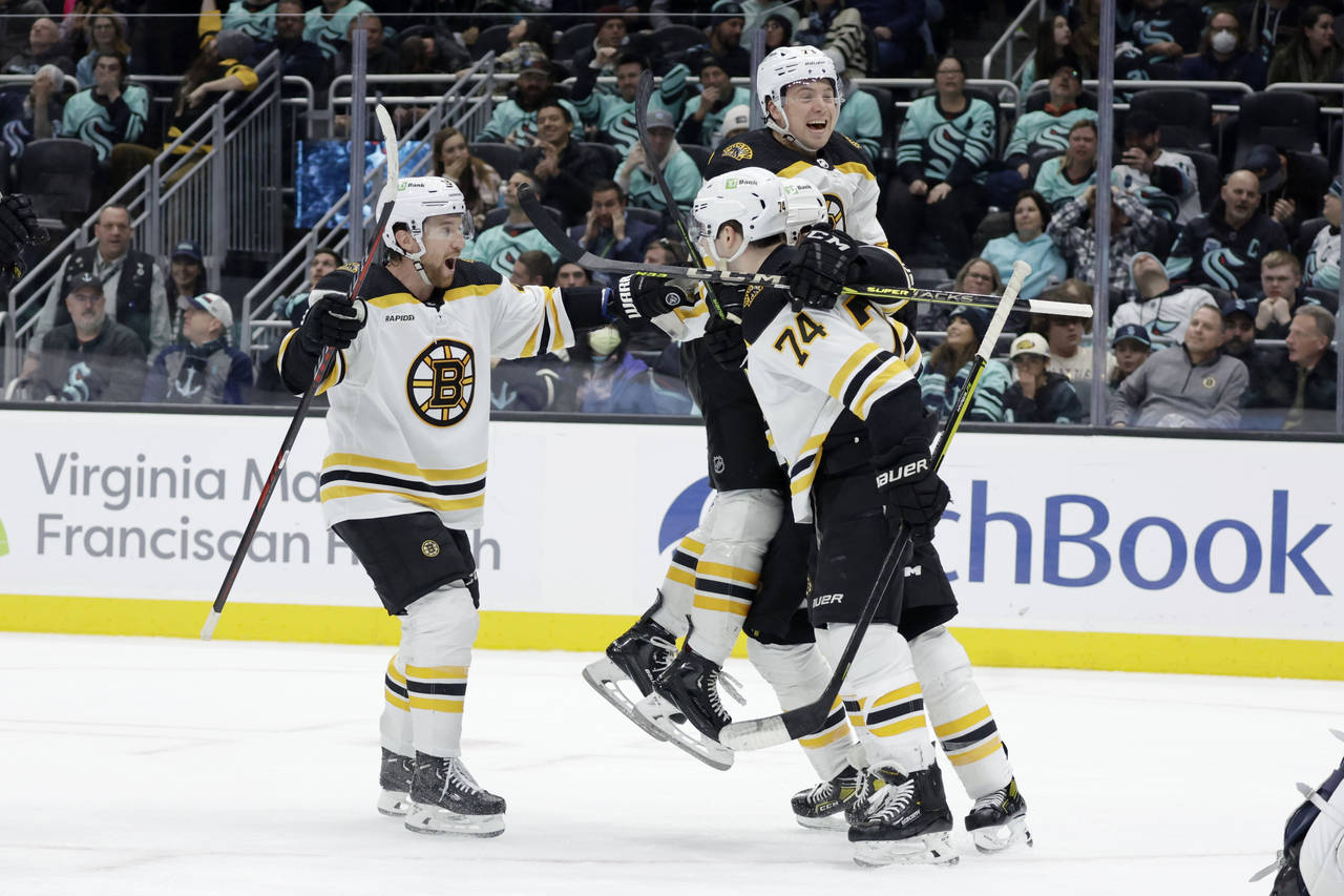 Boston Bruins defenseman Matt Grzelcyk, left, Charlie McAvoy, top, and a teammate celebrate a goal ...
