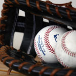 
              FILE -  Two baseballs and a glove are left in the Milwaukee Brewers dugout prior to a spring training baseball game against the Cleveland Guardians on March 29, 2022, in Goodyear, Ariz. Spring training starts Monday in Florida and Arizona for players reporting early ahead of the World Baseball Classic. (AP Photo/Ross D. Franklin, File)
            