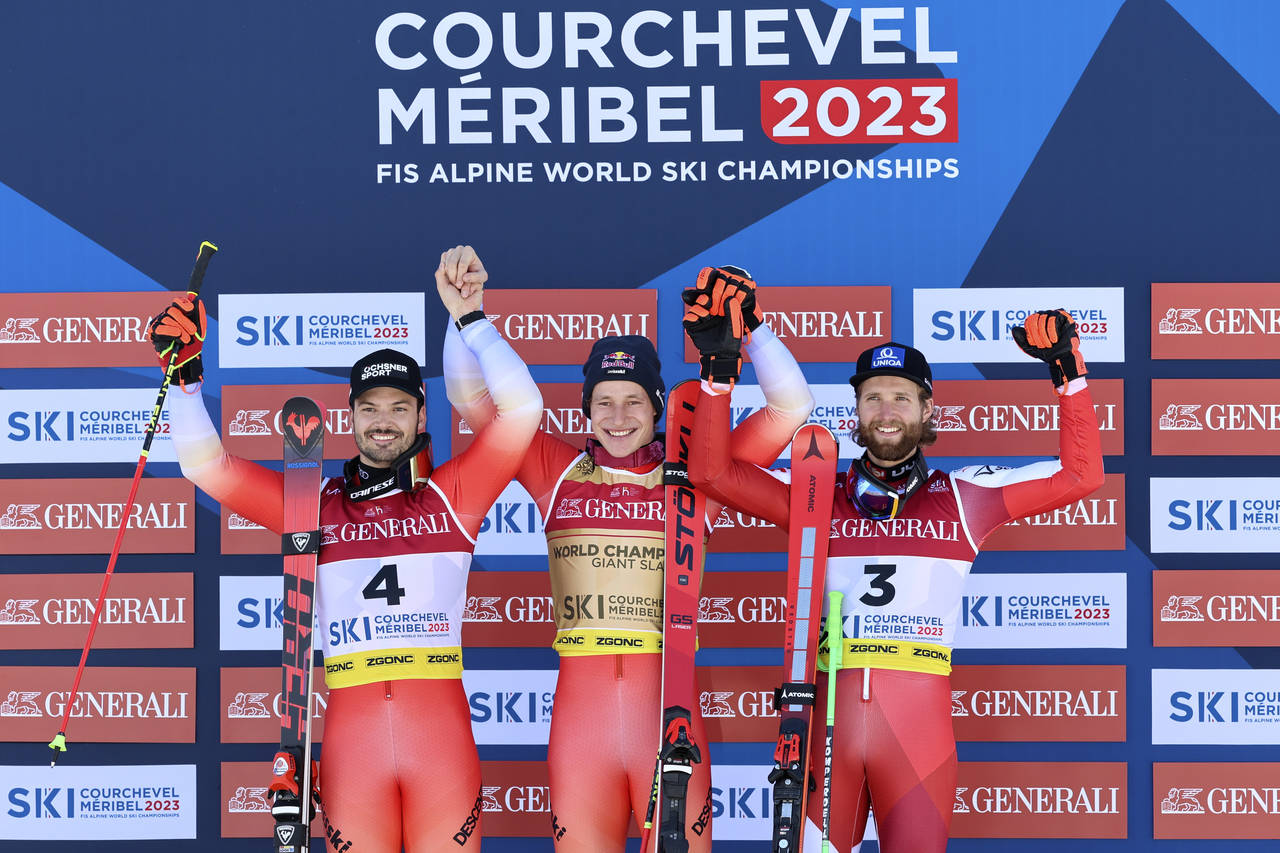 Switzerland's Marco Odermatt, center, celebrates winning gold in an alpine ski World Championships ...