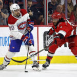 
              Montreal Canadiens' Alex Belzile (60) clears the puck around Carolina Hurricanes' Jalen Chatfield (5) during the second period of an NHL hockey game in Raleigh, N.C., Thursday, Feb. 16, 2023. (AP Photo/Karl B DeBlaker)
            