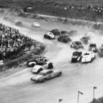
              FILE - Cars take a turn during the first lap of a NASCAR Sportsman's stock car auto race in Daytona Beach, Fla., Feb. 24, 1954. (AP Photo, File)
            