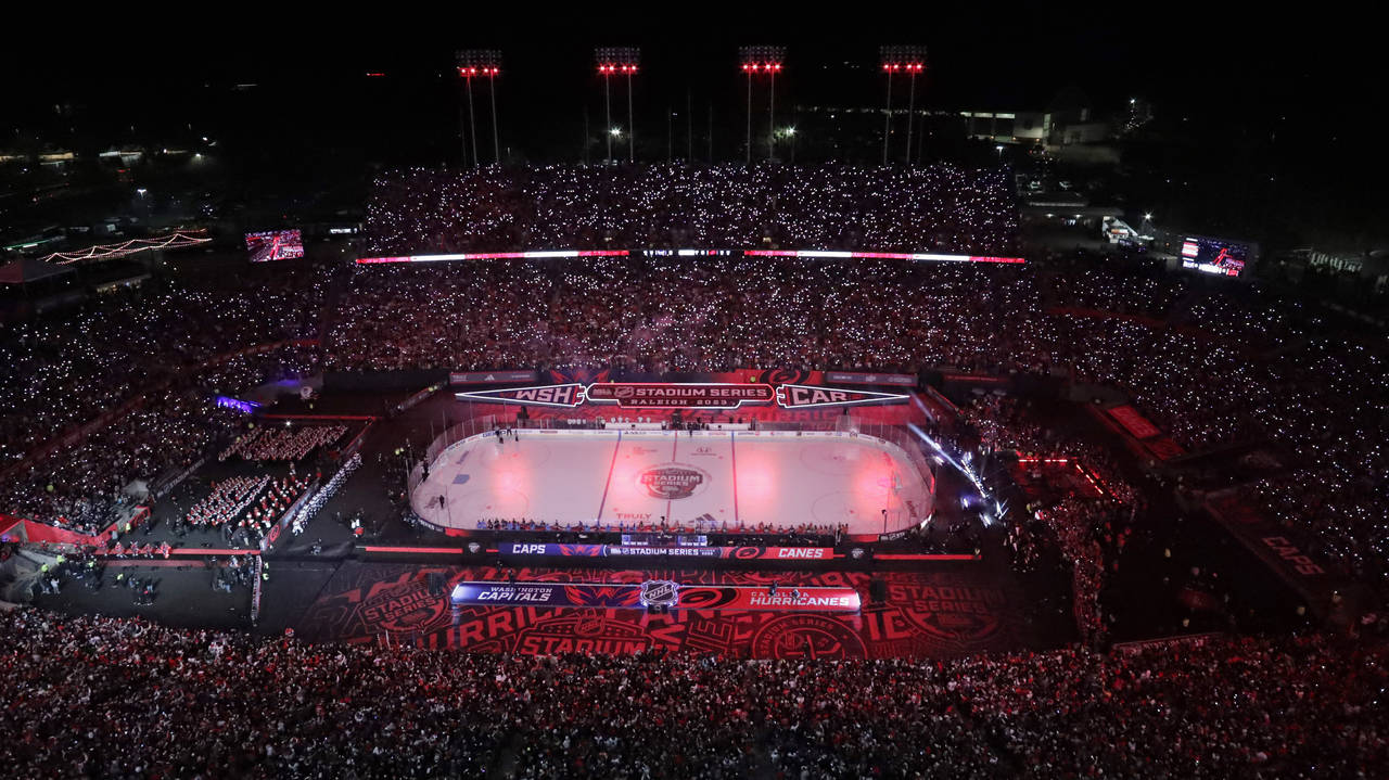Fans hold lighted cellphones as the lights are dimmed before an NHL hockey Stadium Series game betw...