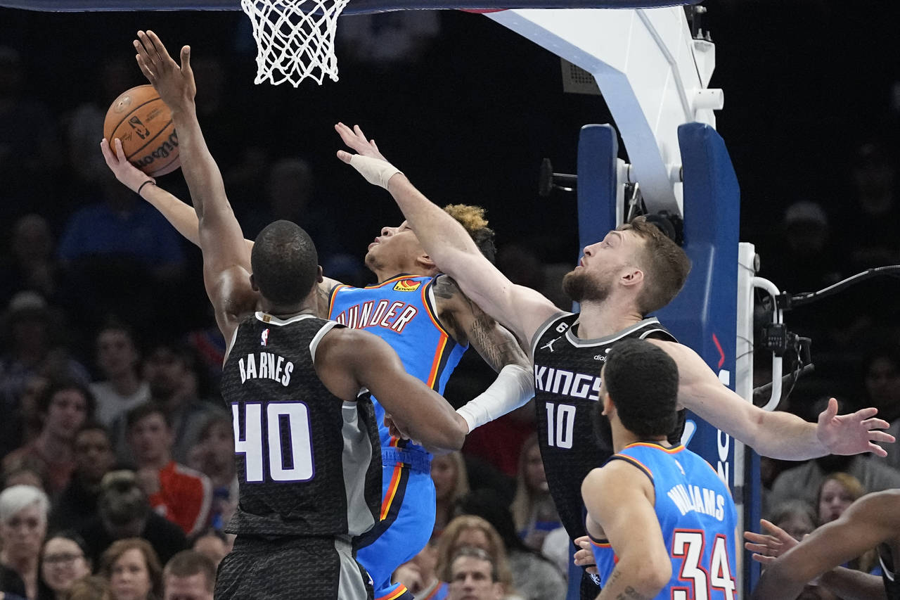 Oklahoma City Thunder guard Tre Mann, center, shoots between Sacramento Kings forward Harrison Barn...