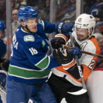 
              Vancouver Canucks' Jack Studnicka, left, hits Philadelphia Flyers' Scott Laughton along the boards during the first period of an NHL hockey game Saturday, Feb. 18, 2023, in Vancouver, British Columbia. (Rich Lam/The Canadian Press via AP)
            