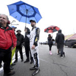 
              Ross Chastain, center, stands under an umbrella after exiting his race car on the pit lane after rain stopped the NASCAR Xfinity Series auto race after only two pace laps, Saturday, Feb. 25, 2023, at Auto Club Speedway in Fontana, Calif. (Will Lester/The Orange County Register via AP)
            