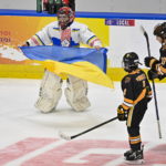 
              Ukraine peewee team goalie Matvii Kulish, left, celebrates his team's victory by holding the Ukraine flag as Boston Junior Bruins Patrick Fennell and Brendan O'Toole skate by at the end of a hockey game, Saturday, Feb, 11, 2023, in Quebec City. (Jacques Boissinot/The Canadian Press via AP)
            