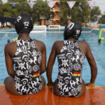 
              Two girls sit poolside in swimsuits during an Awatu Winton Water Polo Club competition at the University of Ghana in Accra, Ghana, Saturday, Jan. 14, 2023. Former water polo pro Prince Asante is training young players in the sport in his father's homeland of Ghana, where swimming pools are rare and the ocean is seen as dangerous. (AP Photo/Misper Apawu)
            