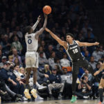 
              Xavier guard Souley Boum (0) shoots a three-pointer against Providence's Noah Locke (10) during the second half of an NCAA college basketball game, Wednesday, Feb. 1, 2023, in Cincinnati. (AP Photo/Jeff Dean)
            